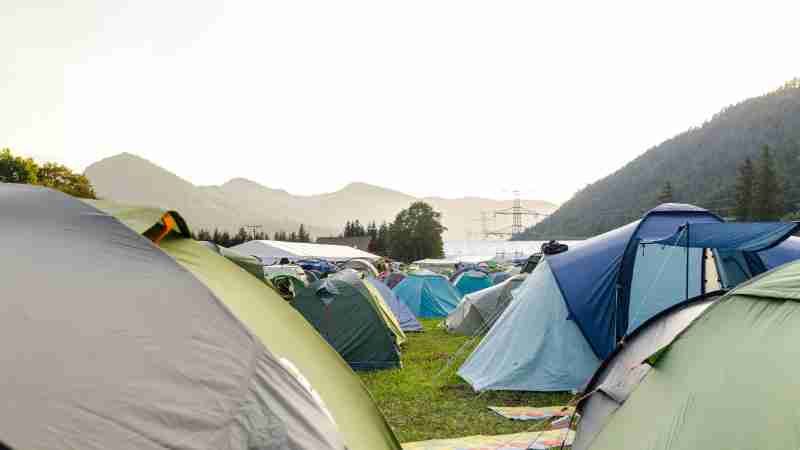 A peaceful campsite with numerous tents nestled among green mountains during summer., tags: brandenburgs - pexel